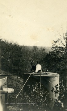 Unknown person kneeling on top of an oil well.