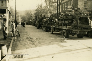 Trucks loaded with scrap metal, driving through town. Many citizens pitched in to support the war effort by collecting materials for recycling.