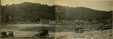 Large crowd and automobiles outline the playing field to watch a baseball game. The teams are not identified.