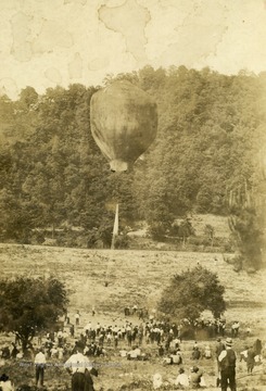 People watch as a man goes up in a hot air balloon.