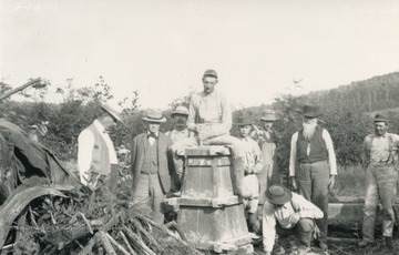 Far left: Samuel Garnett (U.S. geological surveyor), Second from left: William McColloh Brown (Maryland commissioner). Worker sits atop mold for a new marker.