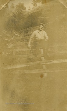 Sherman Ball holding a revolver and shotgun while perched on top of a fence in Breckenridge County, Kentucky. Back of picture says "To Mother and Dad".