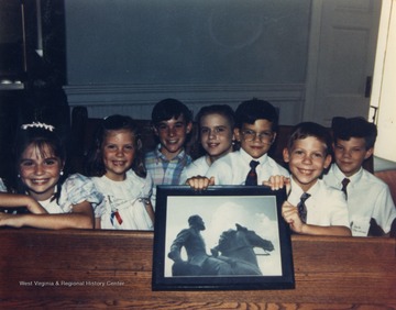 Seven of Stonewall Jackson's great-great grandchildren in his pew in the Lexington Presbyterian Church [where Jackson worshiped for almost ten years before leaving to serve the Confederacy in the Civil War]. The children holding a photo of the Clarksburg (West Virginia) Statue of General Jackson, are L to R: Julia (Julie) Christian, Mary Elizabeth Christian, Thomas Jonathan Jackson Christian III, Virginia Choate, Warren Christian, James Choate, William Jackson (Jack) Christian.  Color photo by Rev. William Edmund Christian II, great grandson of Stonewall Jackson.  