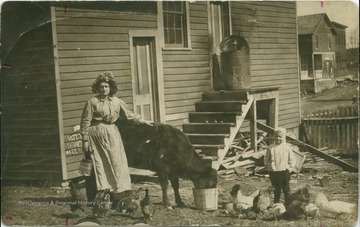 Postcard photograph of Lucy Maxwell Quesenberry and her son Ray, tending to the livestock. 