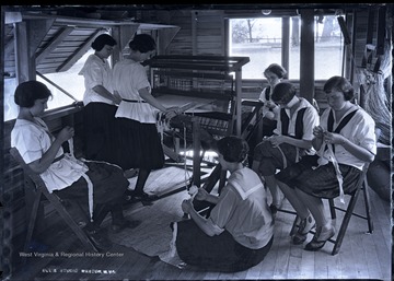 Campers use a loom to weave cloth.