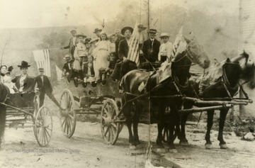 Identified; far left-center, "Aunt" Mae Howard (in the buggy holding a baby); in the back of the wagon, standing sixth from right, Jessie Chaplin; Standing in the front-center of the wagon, Will Howard. Inscribed on the photograph, "The photograph was taken at the foot of the town hill in front of the old building built for the Baptist Church and upstairs Odd Fellow Lodge." Labeled on back: Sara Scott