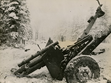 Information included on back: "A wrecked 105mm gun stands by the side of a road near Manhay, Belgium, where troops of the 83rd U.S. Infantry Division are advancing against the northern flank of the Nazi wedge. Manhay was wrested from enemy control December 28, 1944, by Allied forces driving toward the German St. Vith-Laroche supply road which was severed in several places by January 8, 1945, when 15 miles of the vital highway was under U.S. and British control. The Germans were thus left with only one major supply highway into their salient." (U.S. Signal Corps).