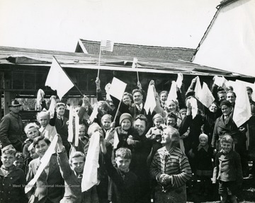 information on back of photo reads: "Smiling civilians of the Bavarian town of Weilheim, Germany, greet troops of the 12th Armored Division, Seventh U.S. Army, with American, British, and Bavarian flags April 28, 1945."