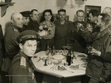 Information on back of photo reads: "Russians and Americans toasting each other after the link up at Torgau. Ann Stringer, U.P. Correspondent can be seen in the picture. Also man with beard on right, who is Correspondent Jack Thompson, of Chicago Tribune."