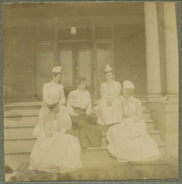 Four nurses and one woman in street clothes, all unidentified, gathered on porch steps at the hospital.