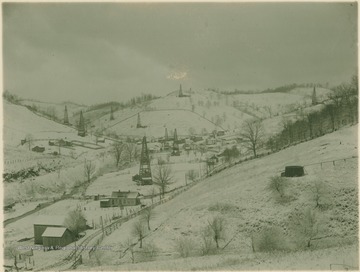 Winter scene with several oil derricks dominating the landscape.
