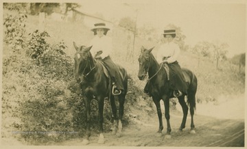 Two women, Grace Shively and Aunt Mae Fleming, mounted and neatly attired, travel a dirt road.