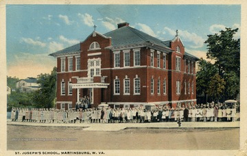 Students lined up outside of red brick school building. See original for correspondence. Published by Louis Kaufmann &amp; Sons. (From postcard collection legacy system.)