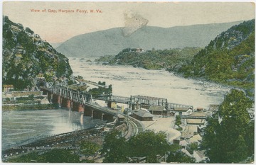 Railroad bridge crosses over the confluence of the Potomac and Shenandoah Rivers into a tunnel. Published by Baltimore Stationery Company. (From postcard collection legacy system.)