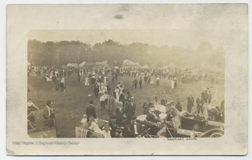 A crowd covers an open field surrounded by old cars and festive tents. (From postcard collection legacy system.)
