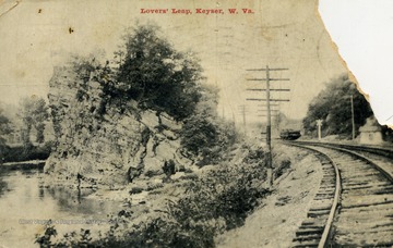 Two people stand atop the giant rock formation to the left of the railroad tracks. See original for correspondence. (From postcard collection legacy system.)