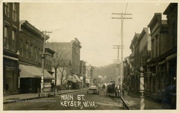 Several horse and buggies travel down Main Street in Keyser, W. Va. See original for correspondence. (From postcard collection legacy system.)