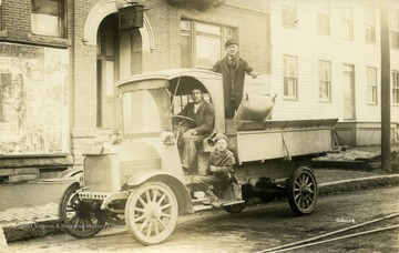 Two men and child travel down University Ave. by truck. (From postcard collection legacy system.)