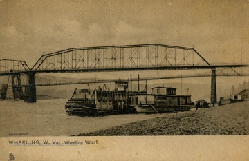 Steel and Suspension bridges visible in distance. Caption on back of postcard reads: "The wharf, bordering the Ohio River, is about 250 yards in extent and is paved with cobble stones. Wheeling exports large quantities of general manufactures, glassware, and potteries, and thousands of vessels land and depart from here, carrying on an extensive commerce on the river." Published by Raphael Tuck and Sons. (From postcard collection legacy system.)