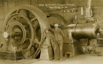 Man stands next to machinery in power house. See original for correspondence. (From postcard collection legacy system.)
