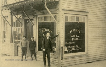 Caption on back of postcard reads: "In 1908 our founder, K.C. Berdine, posed in front of the "new" Berdines Variety Store. The ladies dress hats in the window were 10 cents, but nothing in the store cost more!" (From postcard collection legacy system.)