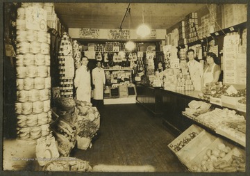 A group of unidentified employees pose in the interior of a grocery shop.