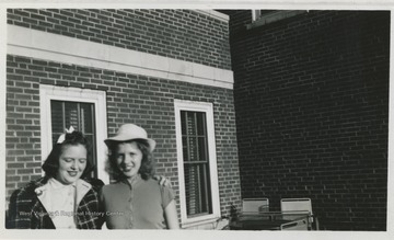 Two female students identified as "Schultzie" and "Margie Frum" pose on the roof of what is now known as Stalnaker Hall of West Virginia University. 