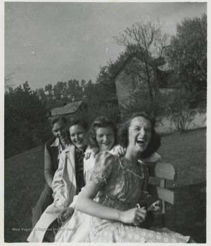 Boy and three girls laugh on a bench as their photo is taken. 