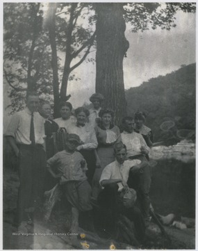 Group poses by the trees along the river. 