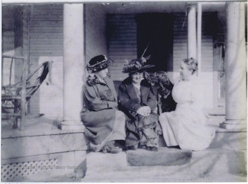 The women sitting on the porch steps with the pet dog. 