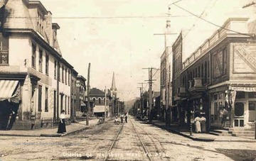 View of brick paved Charles Street with trolley car tracks running down the middle.