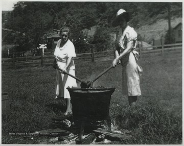 Two unidentified women cooking over a fire.