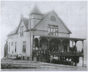 A group poses in front of the building. The building was later destroyed by a fire on December 3, 1911.