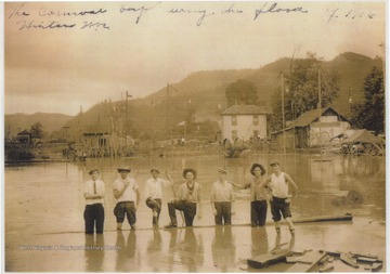 A group of boys wade in the knee-high flood water. Subjects unidentified.