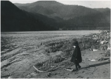 A young girl is pictured by the river bank looking toward Madams Creek. Subject unidentified. 