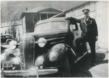 Ailstock in uniform posing with an automobile.