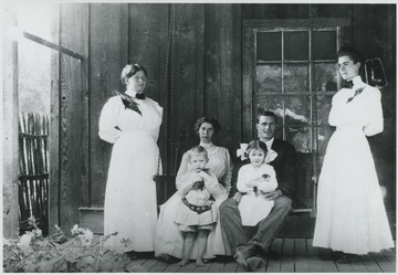The family poses on the porch. Subjects unidentified.