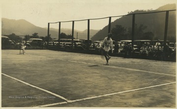 Spectators watch on the court from behind the tennis player. Subjects unidentified. 