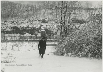 A young boy walks through the snow. MX Cabin seen in the background. Subject unidentified. 
