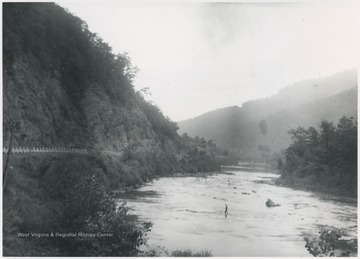View from Foss Bridge near Hinton, W. Va. An unidentified man is pictured walking across the shallow waters. 