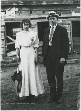 The couple is pictured in front of the old log cabin.