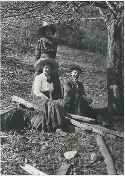 Three unidentified people pictured next to a tree. 