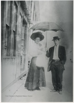 A man holds an umbrella over a woman holding a baby. Subjects unidentified. 