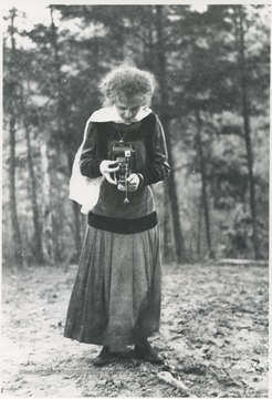 An unidentified woman adjusts the camera in her hands.