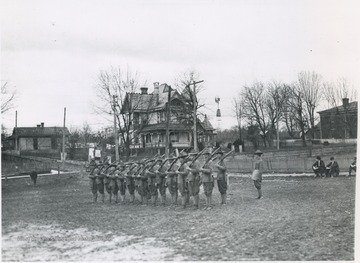 Enlisted soldiers are line in drill position awaiting instruction with rifles over their shoulders. Subjects unidentified. 