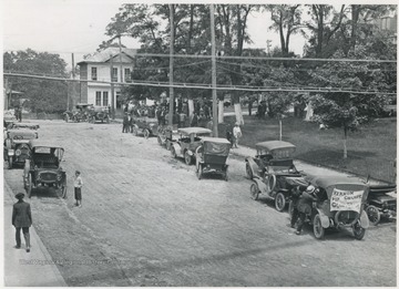 An automobile advertises Vernon Champe for Congress. In the background can be seen a gathering crowd.
