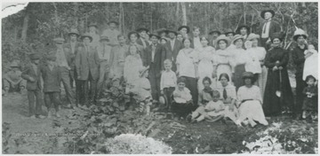 A group of all ages is pictured by the trees. 