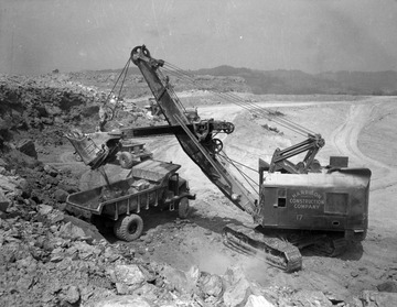 Harrison Construction Company of Pittsburgh, Pennsylvania grading the Kanawha Airport site, circa 1945 or 1946, using a Northwest 80-D shovel to load a Euclid 15-ton capacity rear dump truck with shot rock.