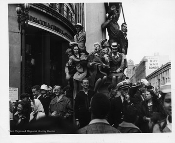 People posing on pillar, celebrating the surrender of Japan during World War II.
