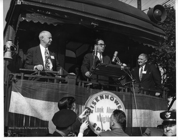 Holt delivers a speech from the back of a train during his 1952 campaign for West Virginia Governor. The name of the train was the 'Eisenhower Special', after General Dwight D. Eisenhower who was running for president. Stamped on the back of the photo, ' Photographic Department Weirton Steel Co., Weirton, West Va.'.